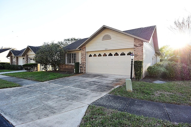 ranch-style house featuring an attached garage, a front yard, concrete driveway, and brick siding