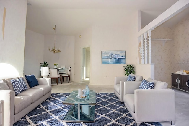 living room with a towering ceiling, a chandelier, and concrete flooring