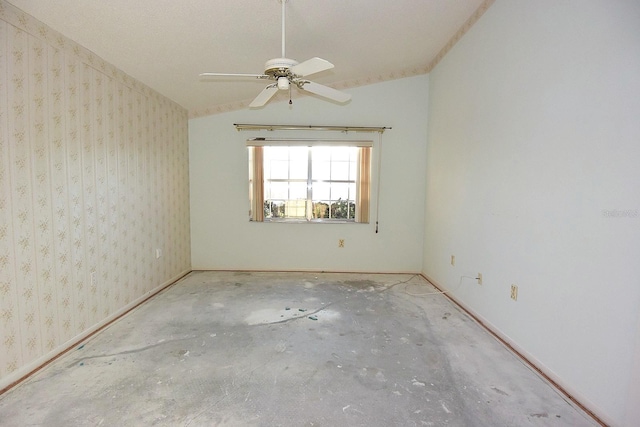 unfurnished room with unfinished concrete flooring, a ceiling fan, vaulted ceiling, baseboards, and wallpapered walls