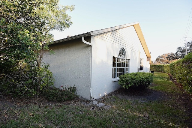 view of side of home featuring fence and stucco siding