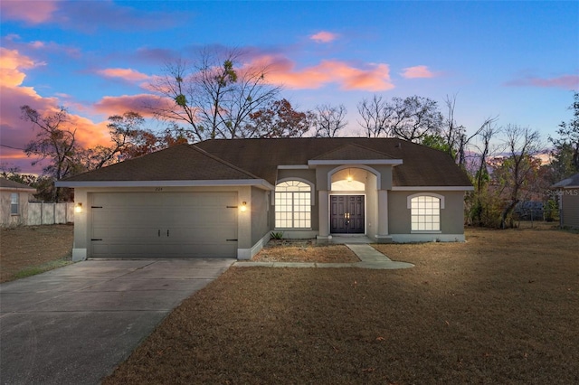 ranch-style house featuring a garage, concrete driveway, a yard, and stucco siding