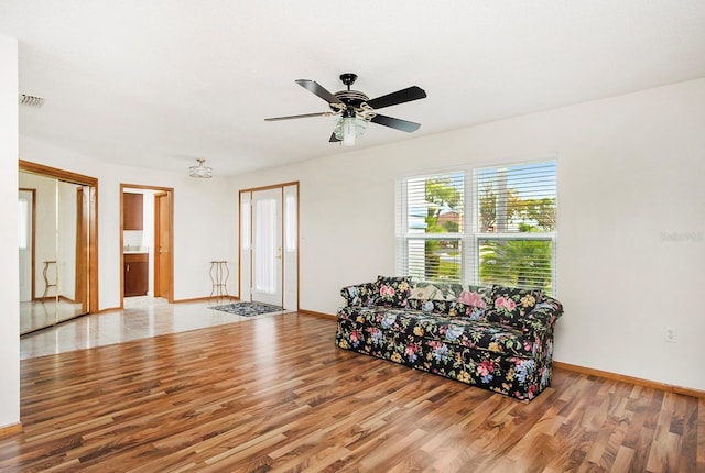 living area with a ceiling fan, visible vents, baseboards, and wood finished floors