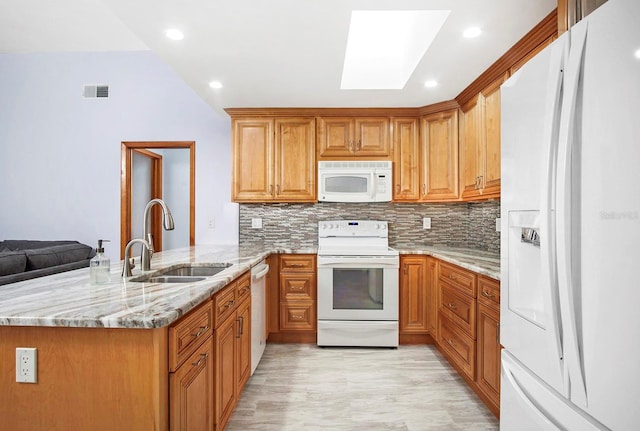 kitchen with white appliances, tasteful backsplash, a peninsula, light stone countertops, and a sink