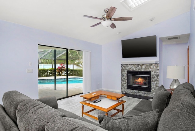 living area featuring a fireplace, lofted ceiling, visible vents, ceiling fan, and wood finished floors