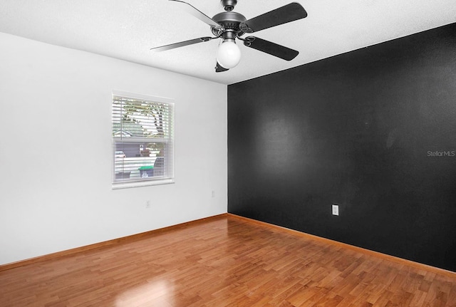 spare room with a ceiling fan, baseboards, and wood finished floors