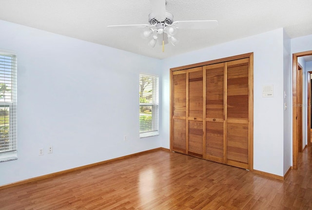 unfurnished bedroom with light wood-style floors, a closet, baseboards, and a ceiling fan