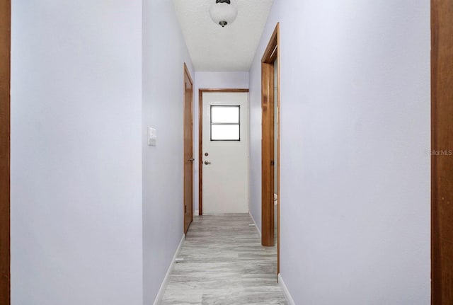 corridor featuring a textured ceiling and baseboards