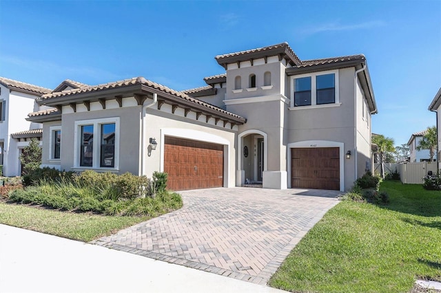 mediterranean / spanish-style home with a tile roof, decorative driveway, and stucco siding