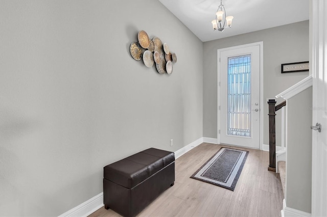 doorway featuring a chandelier, stairs, baseboards, and wood finished floors