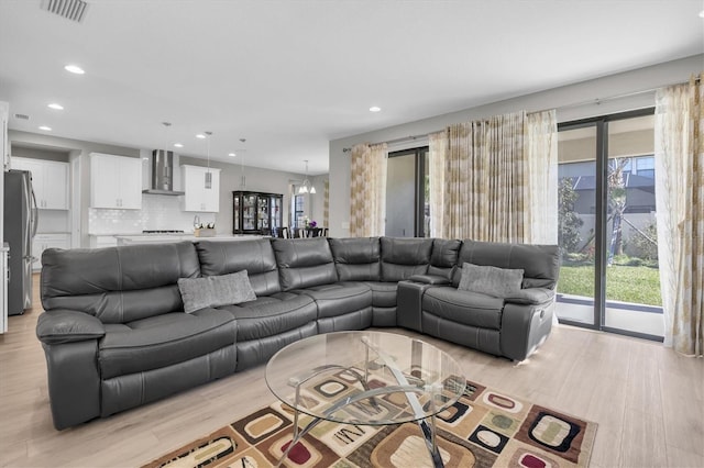 living room featuring light wood-type flooring, visible vents, a notable chandelier, and recessed lighting