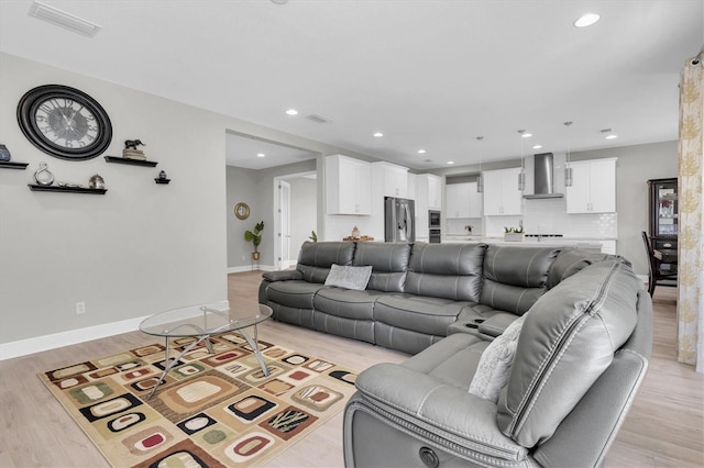 living area featuring light wood finished floors, baseboards, visible vents, and recessed lighting