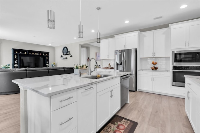 kitchen with stainless steel appliances, open floor plan, a sink, and backsplash