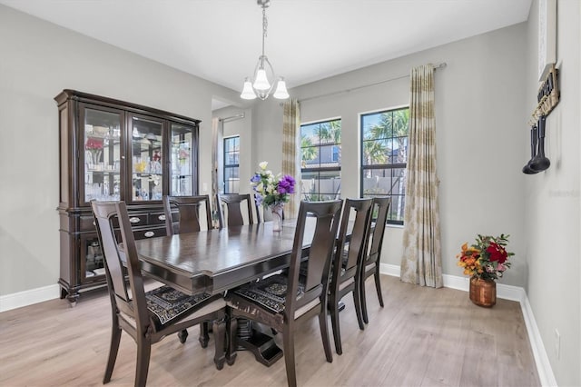 dining area featuring a notable chandelier, light wood finished floors, and baseboards