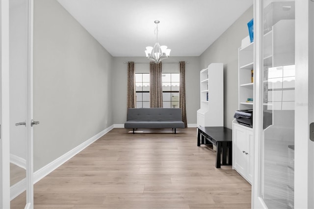 living area with a chandelier, baseboards, and light wood finished floors