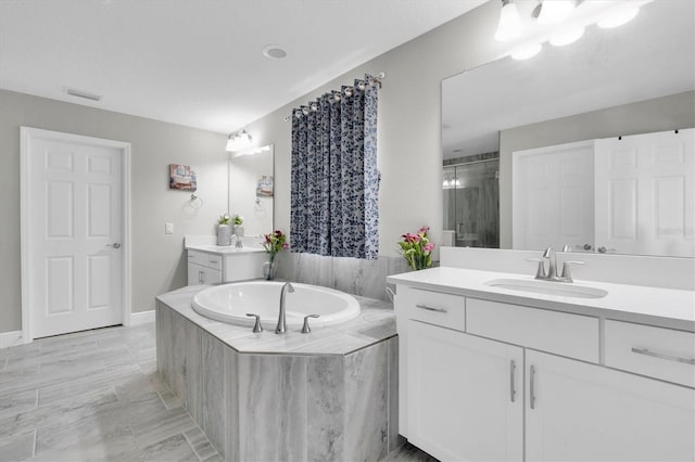 full bathroom with visible vents, a sink, a garden tub, a shower stall, and two vanities