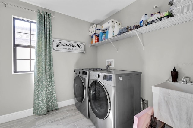 laundry room with laundry area, baseboards, separate washer and dryer, and a sink