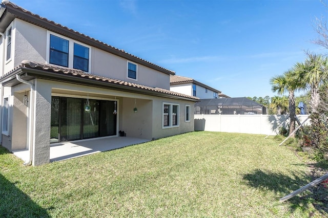 rear view of property with a tile roof, a patio, stucco siding, a lawn, and fence