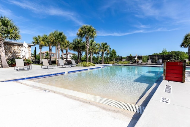 pool with a patio area and fence