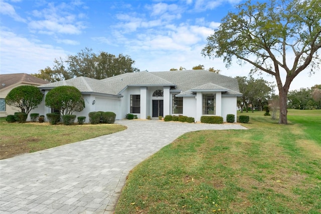 view of front of property with a front lawn, decorative driveway, an attached garage, and stucco siding