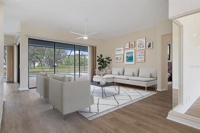 living area with ceiling fan, light wood finished floors, and baseboards