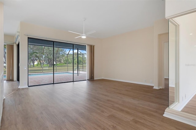 spare room featuring a ceiling fan, a sunroom, baseboards, and light wood finished floors