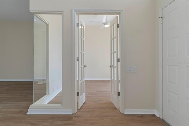 hall with baseboards, wood finished floors, and french doors