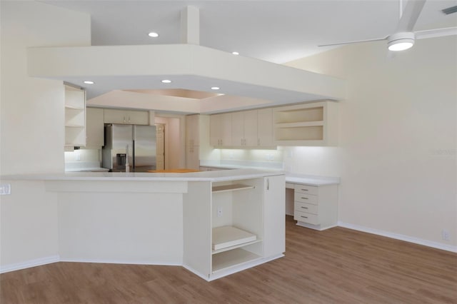 kitchen featuring stainless steel fridge with ice dispenser, wood finished floors, a peninsula, light countertops, and open shelves