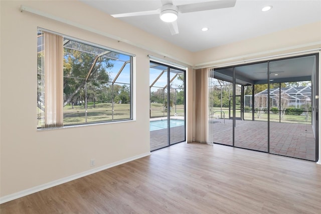 unfurnished room featuring ceiling fan, recessed lighting, wood finished floors, a sunroom, and baseboards