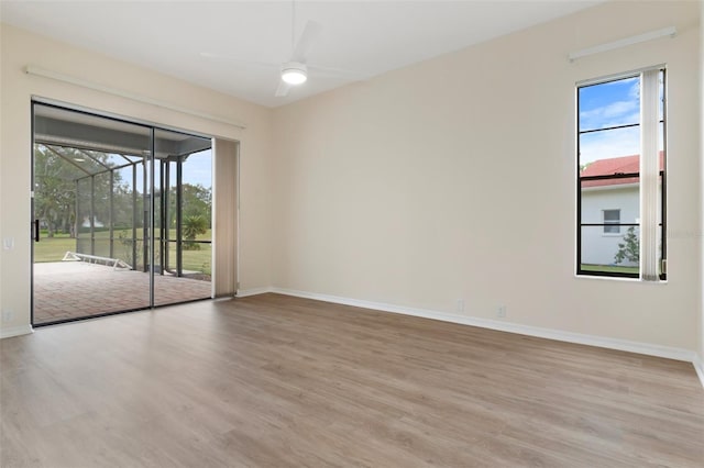 empty room with ceiling fan, light wood-style flooring, and baseboards