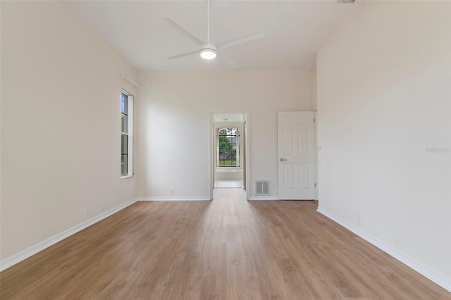 empty room featuring light wood-style floors, baseboards, visible vents, and ceiling fan