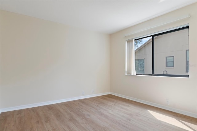 spare room featuring light wood finished floors and baseboards