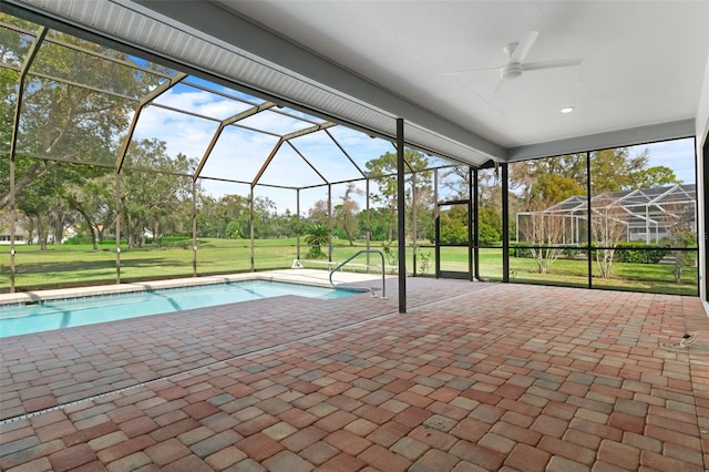 outdoor pool featuring glass enclosure, ceiling fan, a lawn, and a patio