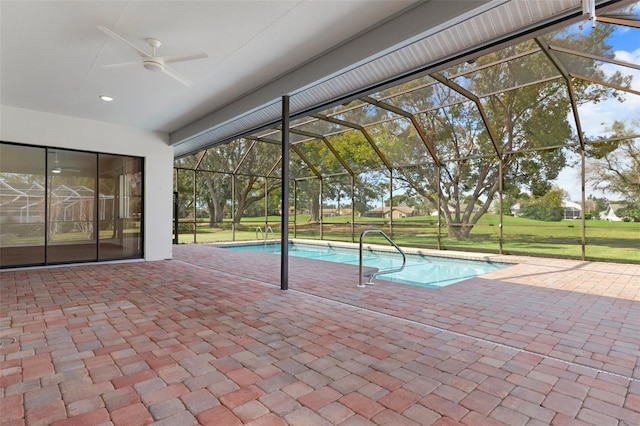 pool featuring glass enclosure, ceiling fan, a patio area, and a yard