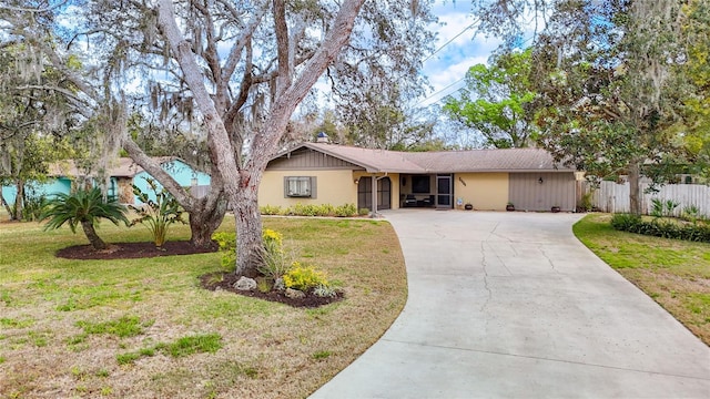 ranch-style house featuring driveway, a front yard, and fence