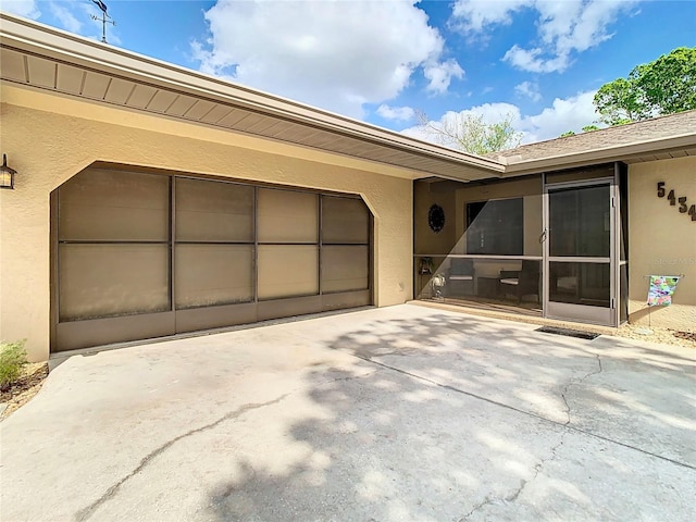 view of exterior entry with driveway, an attached garage, and stucco siding