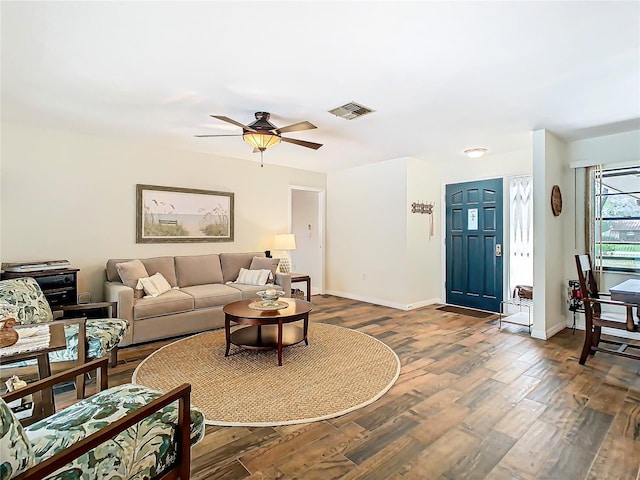 living area with dark wood-style floors, visible vents, ceiling fan, and baseboards