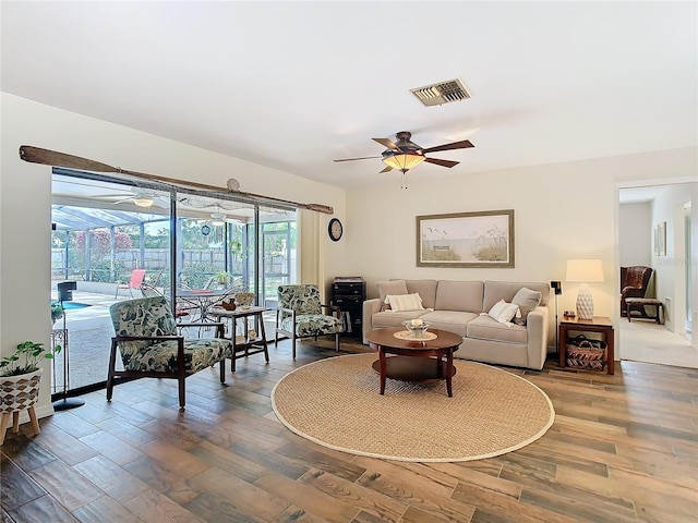 living room featuring a ceiling fan, a sunroom, visible vents, and wood finished floors