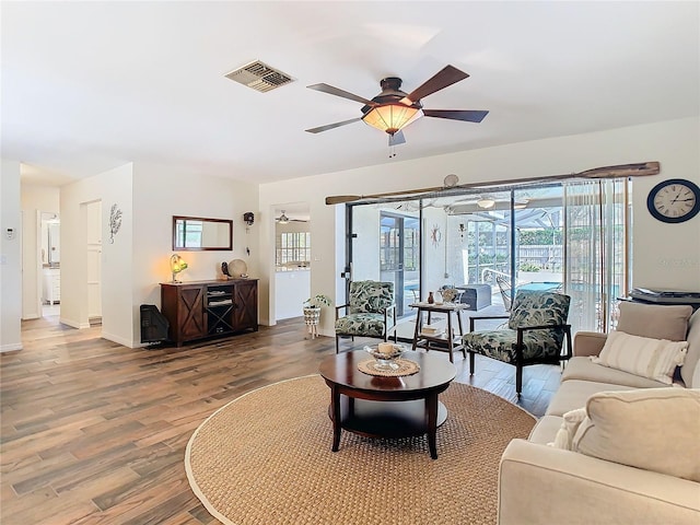 living room with wood finished floors, a sunroom, baseboards, visible vents, and a ceiling fan