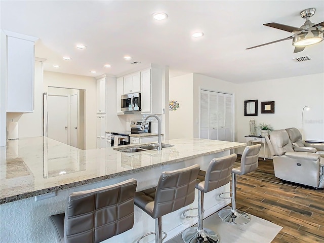 kitchen with light stone countertops, visible vents, stainless steel appliances, and a sink