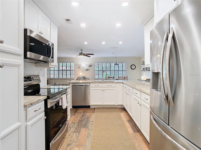 kitchen with appliances with stainless steel finishes, light wood-style floors, white cabinetry, a sink, and recessed lighting