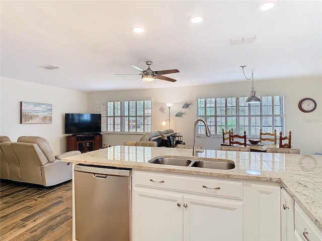 kitchen with a ceiling fan, open floor plan, wood finished floors, stainless steel dishwasher, and a sink