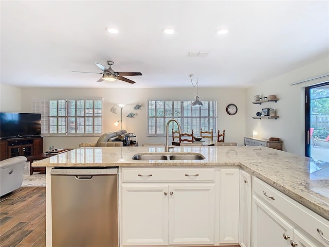 kitchen featuring dark wood-type flooring, a sink, open floor plan, stainless steel dishwasher, and light stone countertops