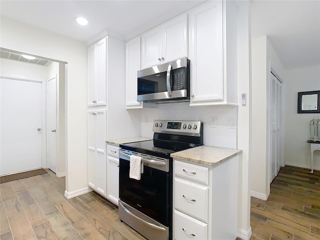 kitchen featuring stainless steel appliances, visible vents, white cabinets, and light wood-style flooring