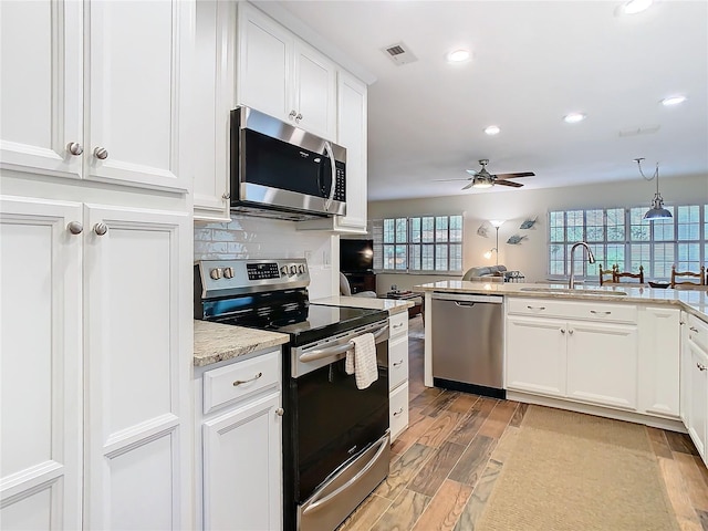 kitchen featuring light wood finished floors, visible vents, a sink, stainless steel appliances, and backsplash