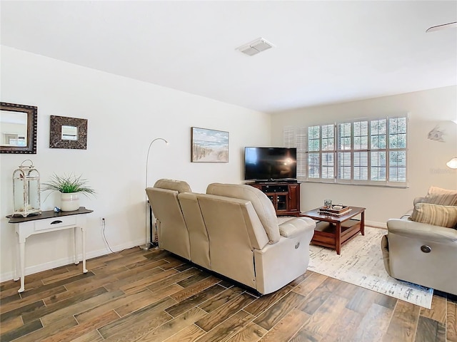 living area with visible vents, baseboards, and wood finished floors