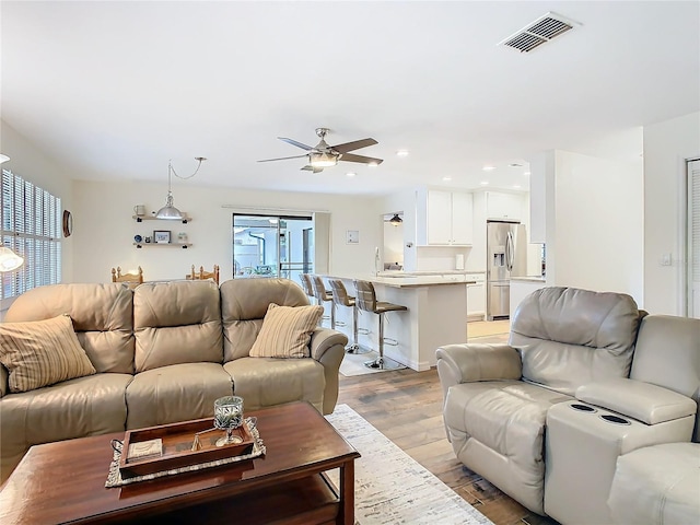 living room with light wood finished floors, visible vents, a ceiling fan, and recessed lighting