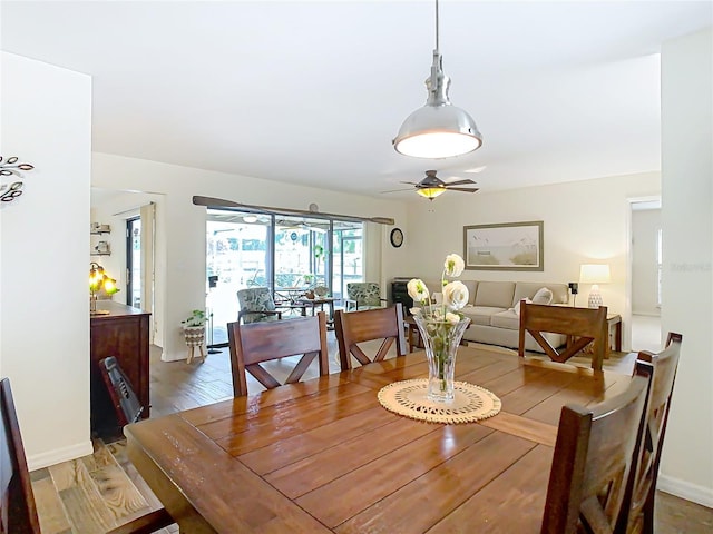 dining room featuring light wood-style floors, baseboards, and a ceiling fan