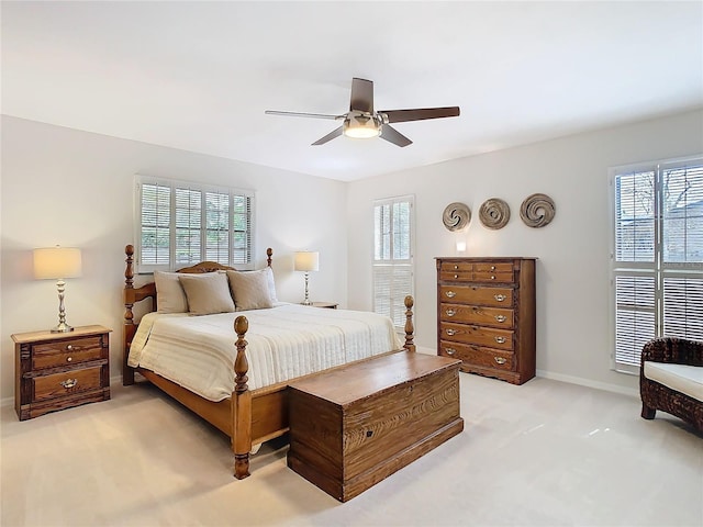 bedroom featuring baseboards, ceiling fan, multiple windows, and light colored carpet