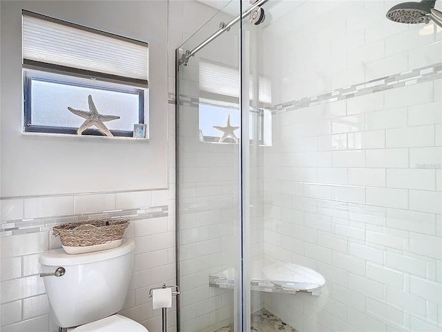 bathroom featuring a stall shower, wainscoting, tile walls, and toilet