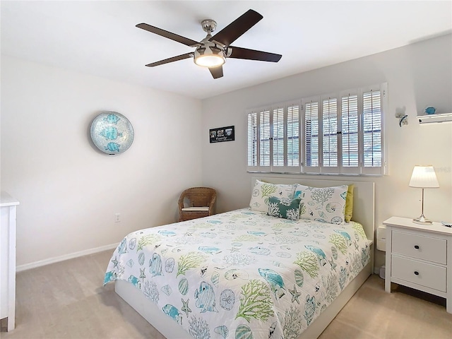 bedroom with a ceiling fan, light colored carpet, and baseboards